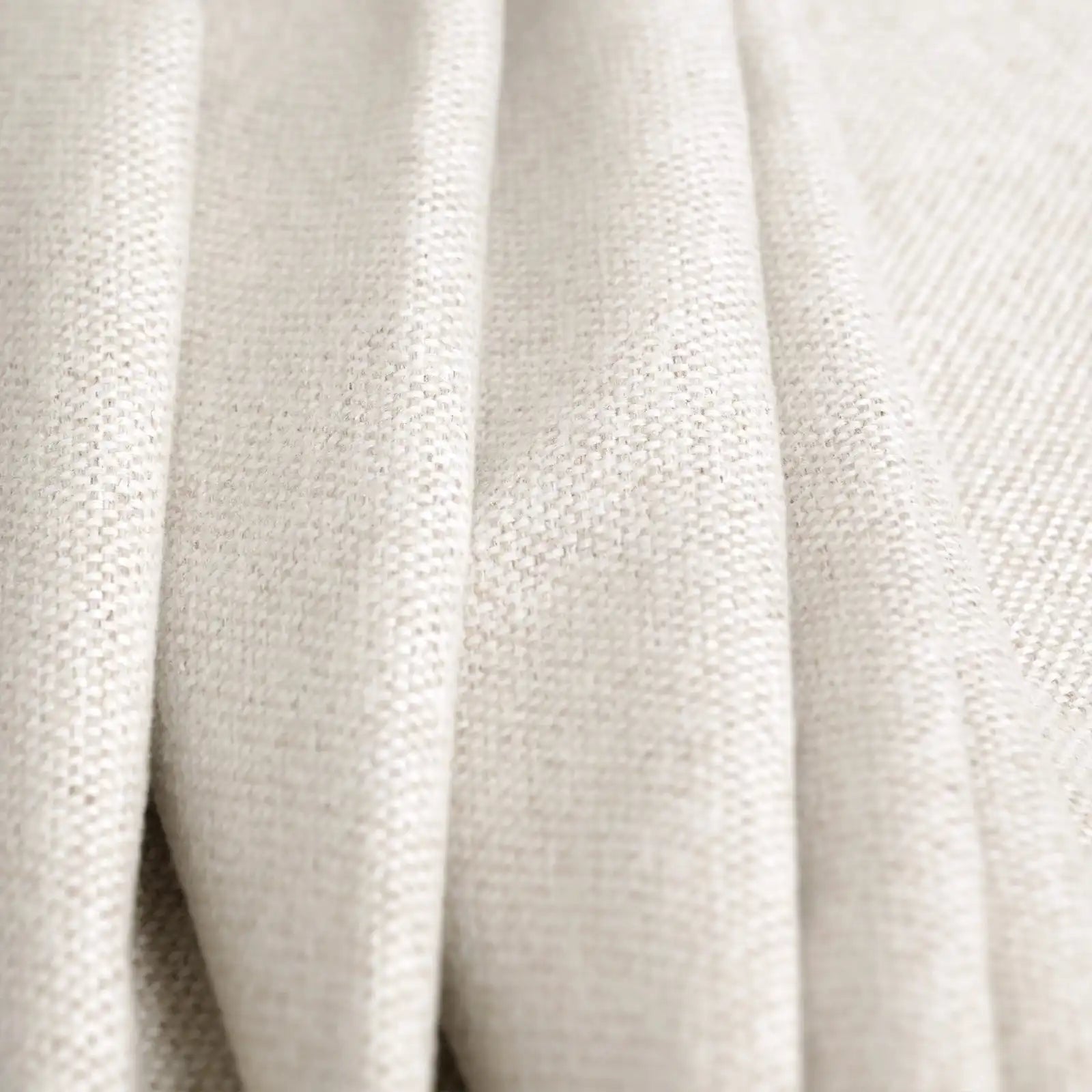 A close-up view of the off-white curtain material arranged in soft, heavy vertical folds, emphasizing its thick fabrication and subtle cream undertones.
