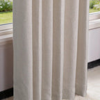 A detailed close-up shot of the off-white curtain hanging by a window, showcasing its clean vertical drapes and the distinct textured weave of the fabric against the outdoor daylight.