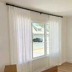 Elegant White Sarah Semi Sheer Curtains hanging on a sleek black rod in a bright room