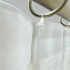 White curtain hooks made of high-polymer plastic securing white fabric curtains on metal rods, close-up view